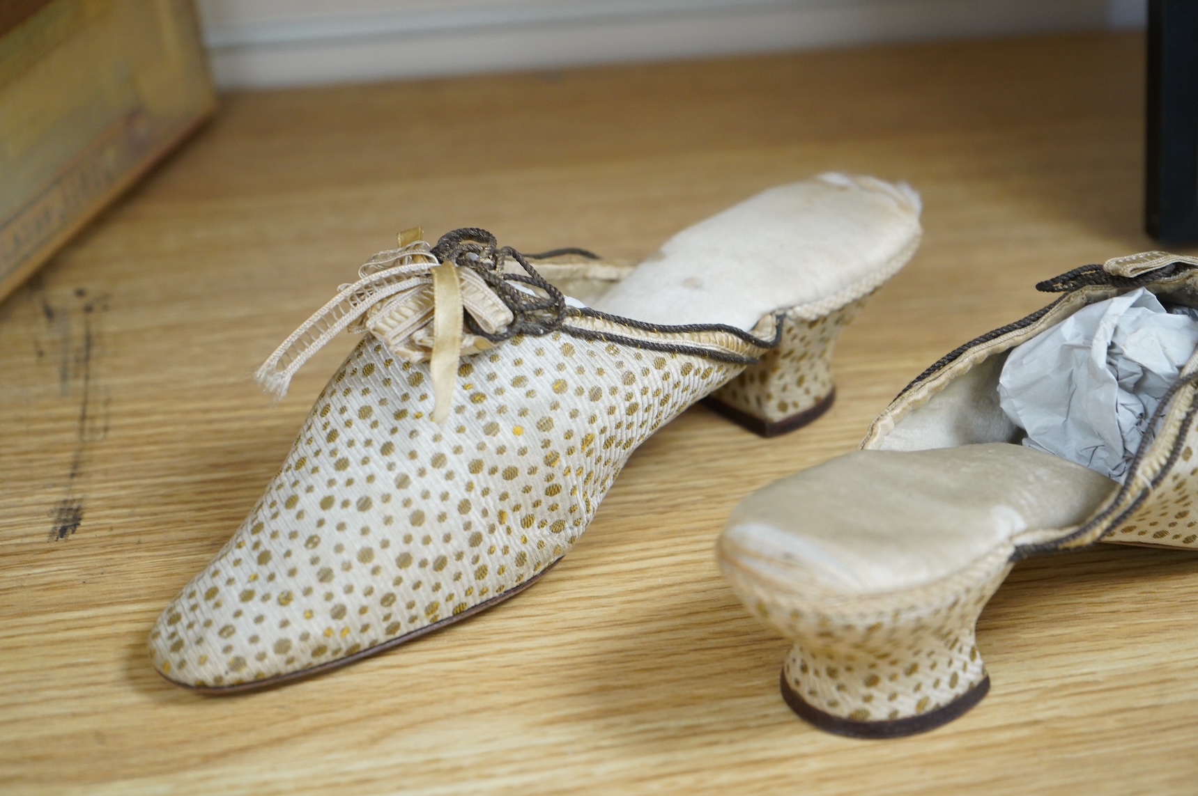 Of interest to collectors and costume designers: a pair of late 19th / early 20th century ladies gold spot embroidered mules, decorated at the front with a rosette of silk ribboning and fine cording. Condition - the cord